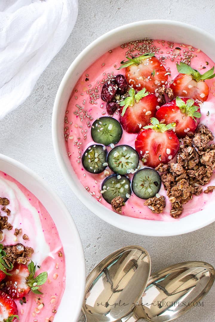 Over head shot of the vegan Strawberry Banana Smoothie Bowl topped with strawberries, blueberries, granola and cranberries.