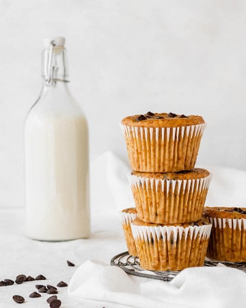 Close up of the Vegan Pumpkin Chocolate Chip Muffins stacked next to a bottle of milk.