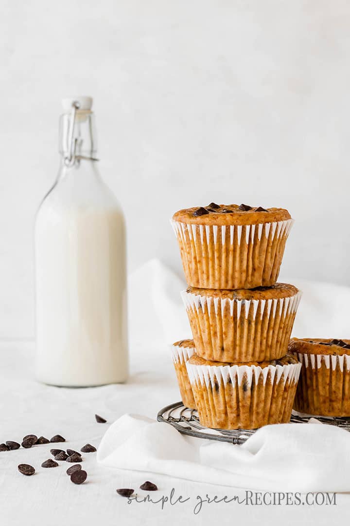 Close up of the Vegan Pumpkin Chocolate Chip Muffins stacked next to a bottle of milk.