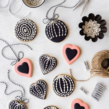 Over head shot of the cookies iced and decorated with sugar pearls, placed on a wooden white surface.