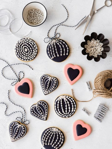 Over head shot of the cookies iced and decorated with sugar pearls, placed on a wooden white surface.