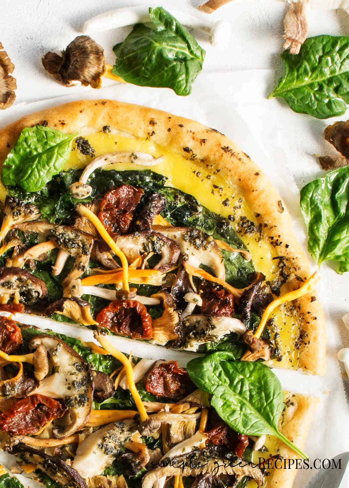 Sliced pizza topped with cheese and veggies and mushrooms against a white background.