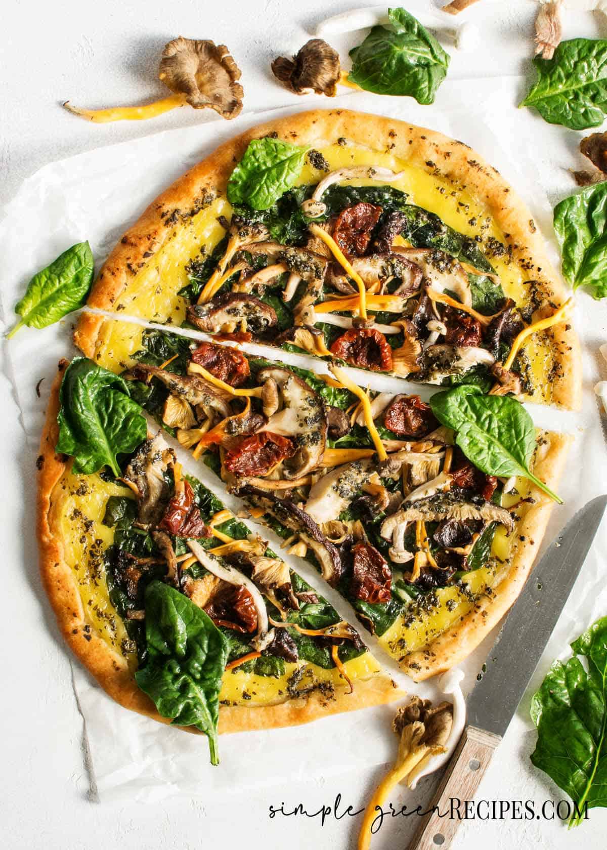 Sliced pizza topped with cheese and veggies and mushrooms against a white background.