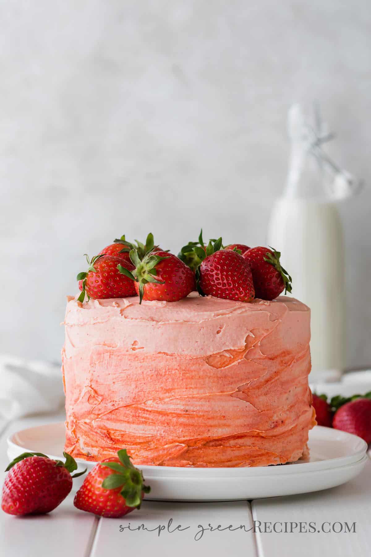 Strawberry cake on a white plate, topped with fresh strawberries