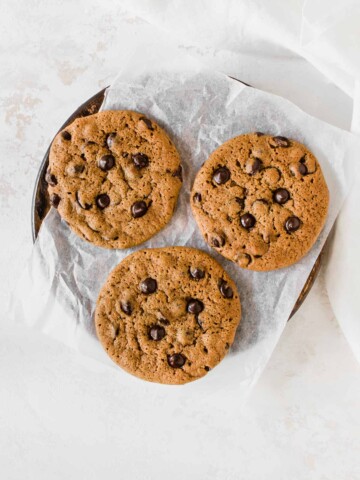 three chocolate chip cookies on a parchment paper