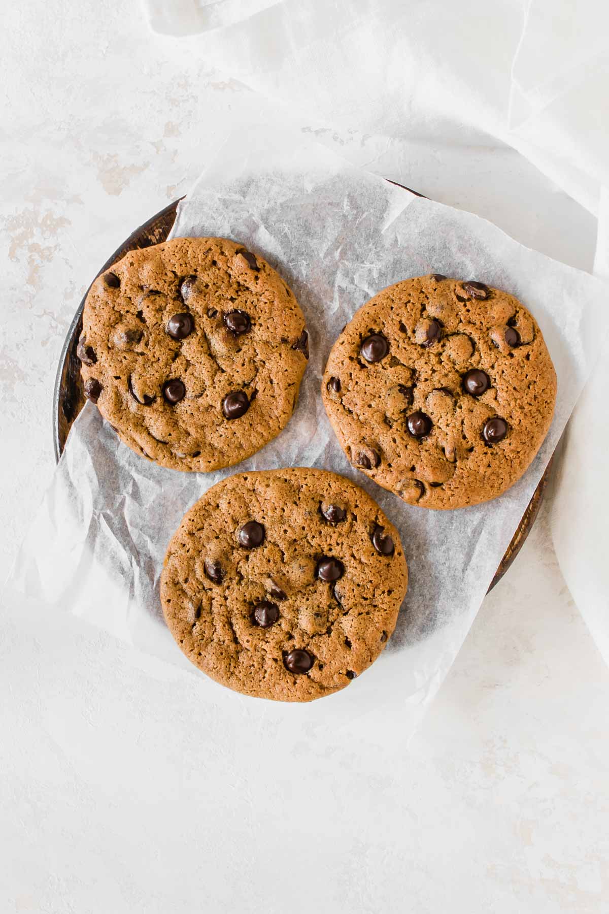 three chocolate chip cookies on a parchment paper