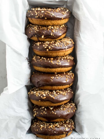 8 donuts frosted with glaze chocolate and crunchy almonds, in a loaf pan lined with parchment paper
