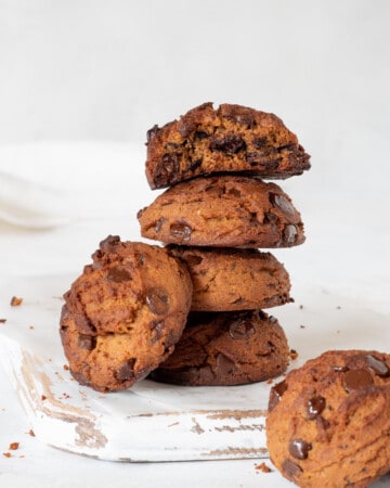 stack of peanut butter cookies with chocolate chips, on a white wooden cutting board