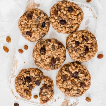 split vegan oatmeal cookie on a white board, surrounded by more cookies