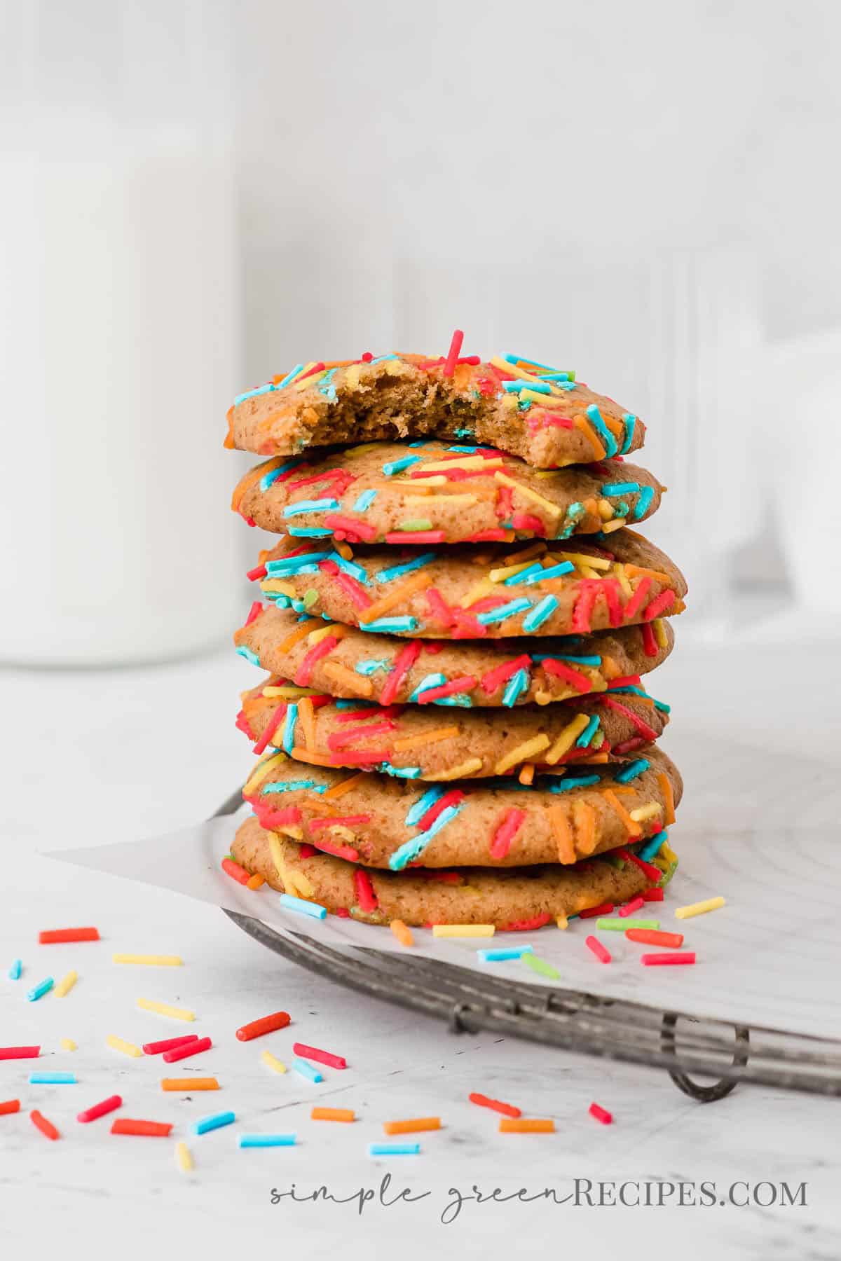 Stack of cookies with sprinkles on a parchment paper over a cooling rack