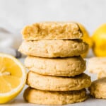 Cookies on a parchment paper over a cooling rack, surrounded by lemons, a dish towel and a wooden squeezer.