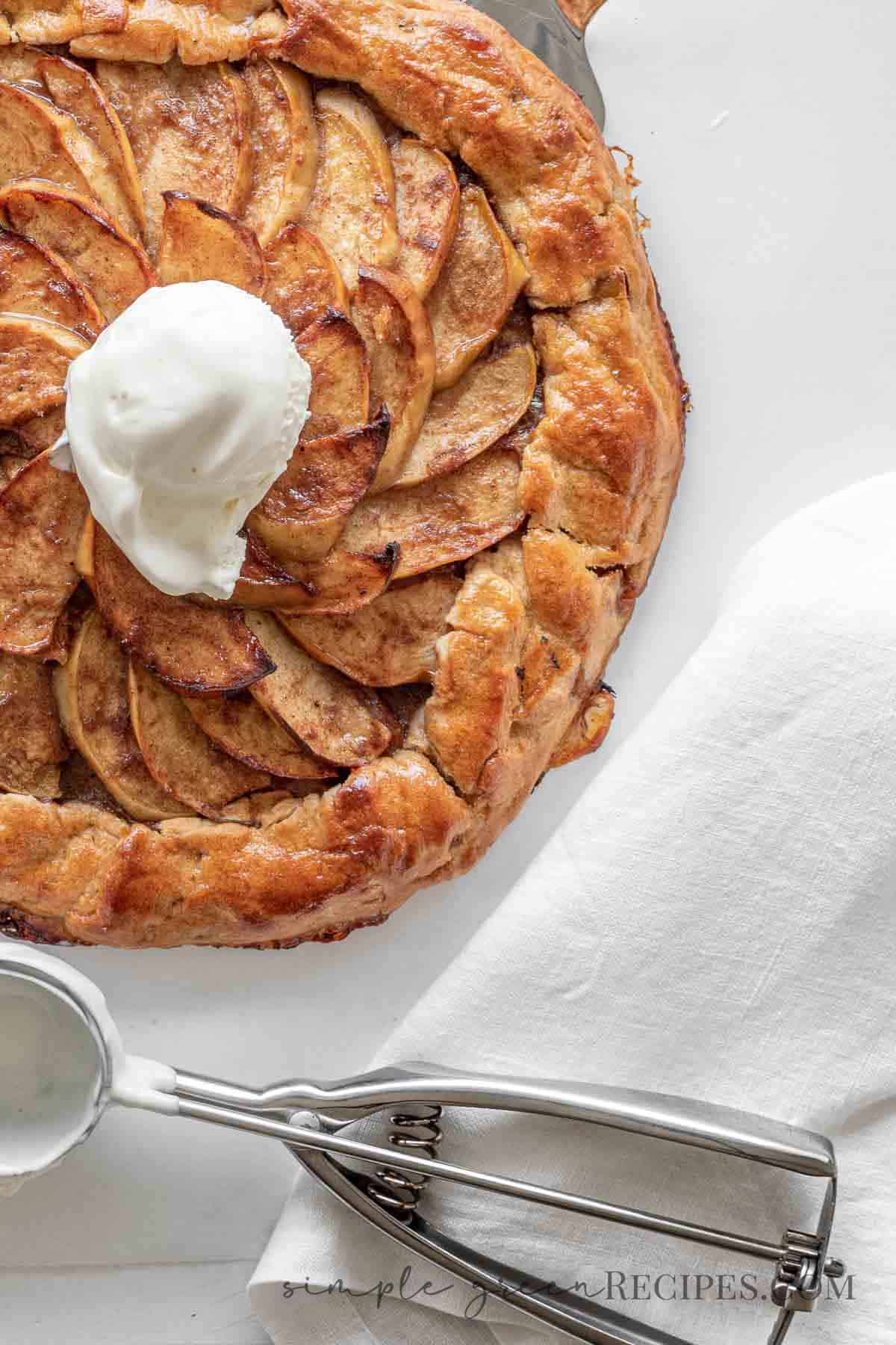 half apple galette toped with ice cream, a napkin and an ice cream server