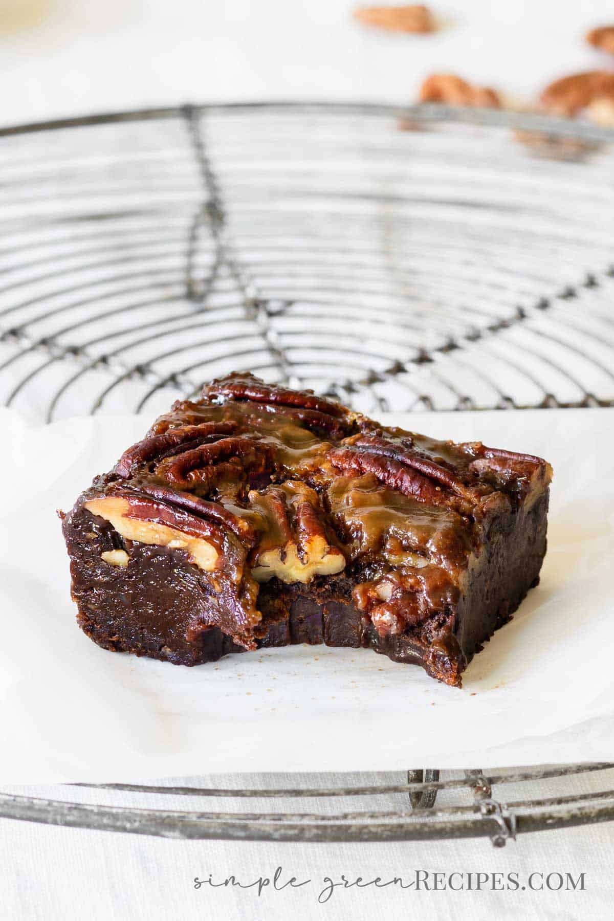 bitten brownie bar topped with pecans, on a cooling rack