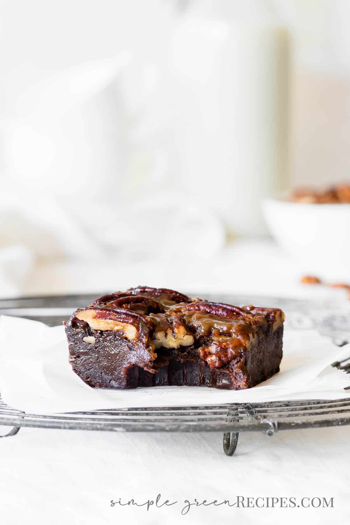 Brownie bar topped with pecans, on a cooling rack