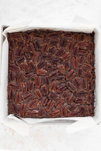 baked brownie topped with pecan pie filling, in a square mould