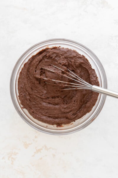 glass bowl with brownie batter and a metal whisk