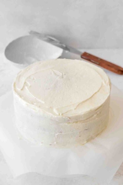 cake covered with white frosting, a bowl and a spatula