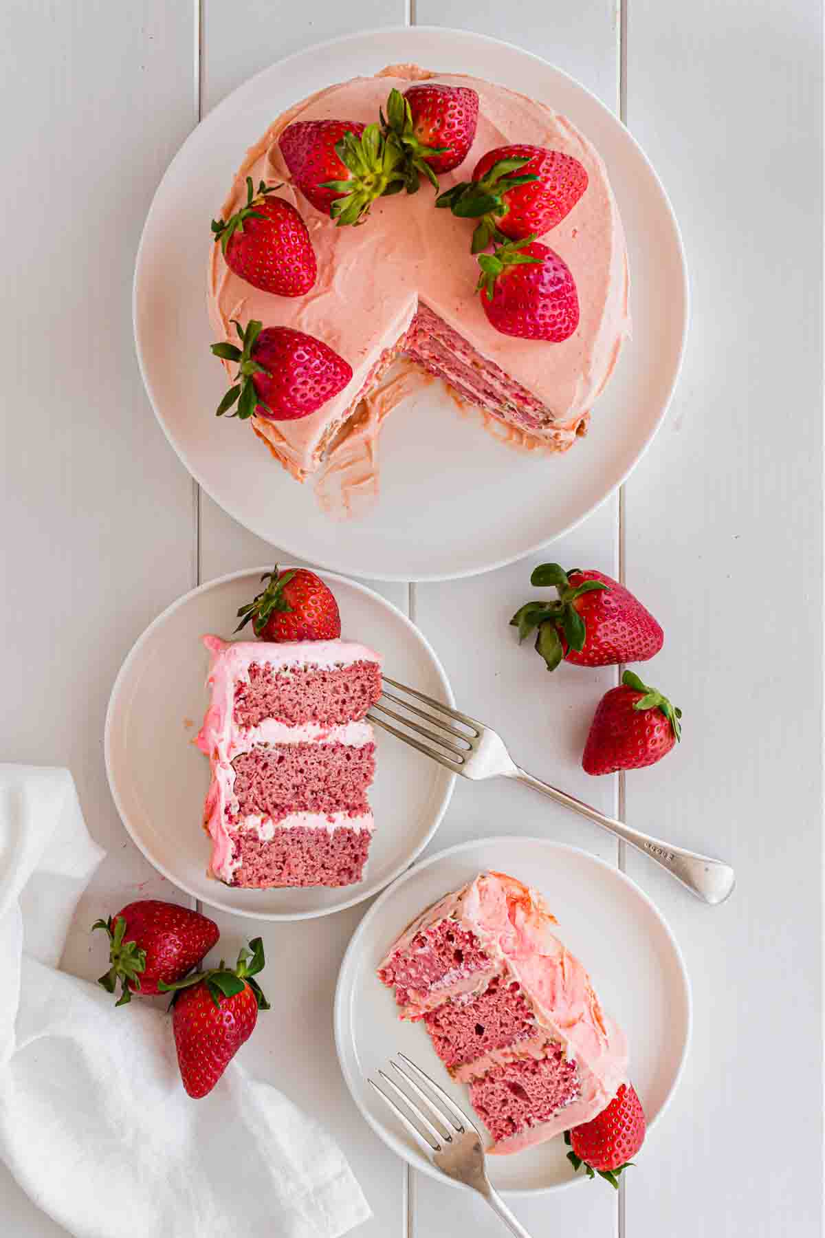 3-layer strawberry cake, sliced and topped with fresh strawberries.